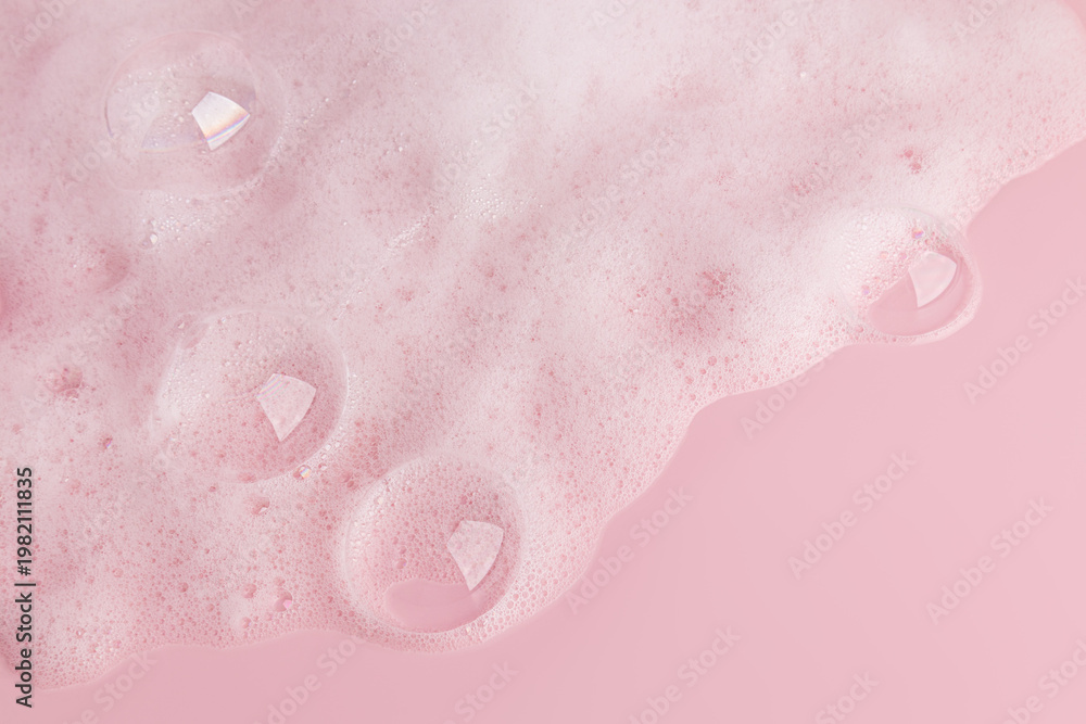 Fototapeta premium Large transparent soap bubbles, soft foam of soap, gel, detergent on a pink background. Hygiene and cleanliness concept. Top view. A copy space