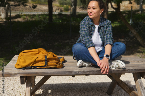 Foto Woman sitting cross legged on table in park and looking away thoughtfully