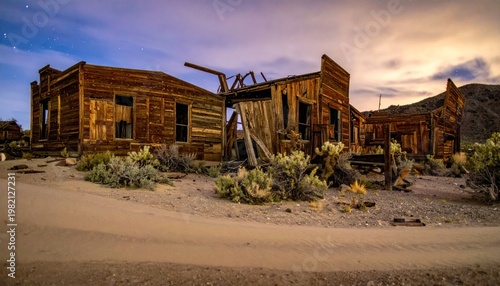 Dilapidated wooden buildings under a twilight sky with sparse desert foliage