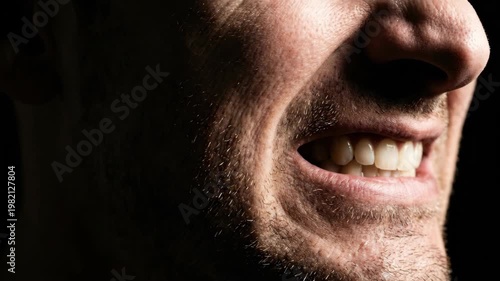 Close up of a mans mouth showing teeth and stubble.