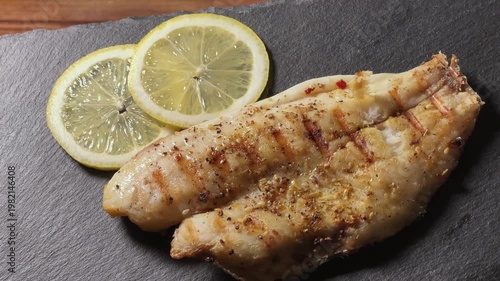 Serving of grilled gilthead fillet on skin on slate plate