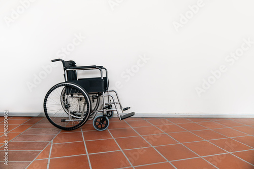 Empty Wheelchair Against White Wall in Minimal Interior Space