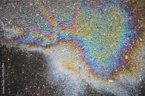 Фотография Oil spill on a damp asphalt surface creating a vibrant iridescent rainbow effect