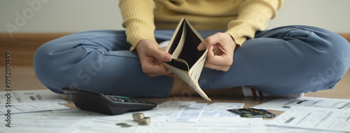 Fotografie The stressed person sitting on the floor opening empty wallet