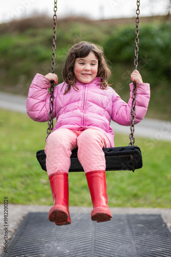 Girl swings happily in a park on a sunny day in spring