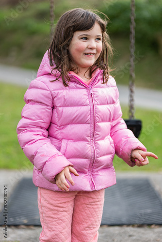 Child plays at the park while wearing a pink jacket and sharing joy