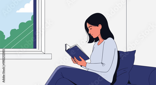 A young woman reading a book while sitting on a cozy sofa indoors by the window