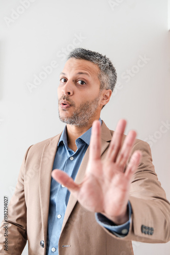Mature businessman holding hand up in stop or wait gesture