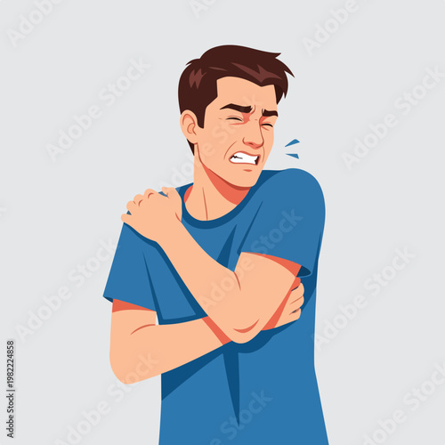 A young man in a blue shirt clutching his painful shoulder with a grimaced face