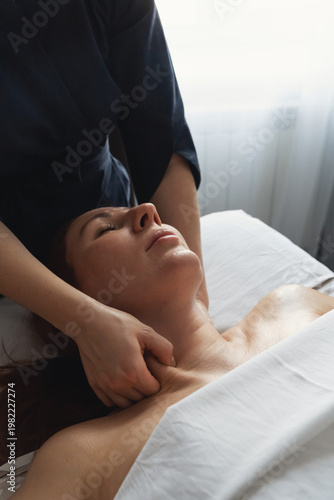 Woman receiving relaxing professional neck and shoulder massage therapy. Client enjoying rejuvenating massage treatment in tranquil spa environment