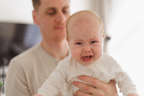 Foto Father holding a crying baby, close-up of distressed infant with red eyes and op