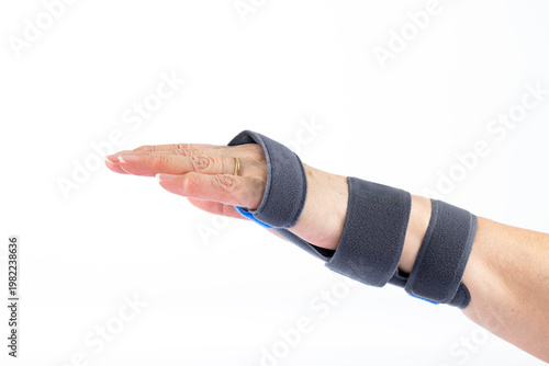 Close up of female hand wearing orthopedic wrist support brace isolated on white background. Medical rehabilitation, injury recovery, carpal tunnel and hand immobilization concept. Side view.
