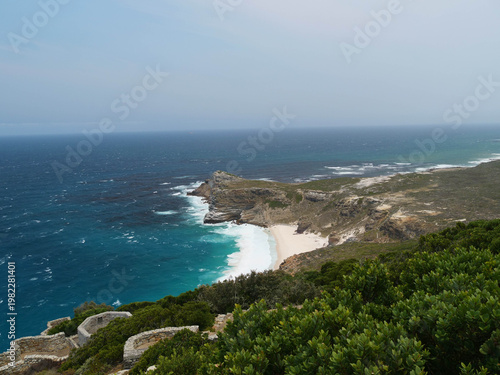 Rugged rocks,  sheer cliffs towering above the beach, sea and ocean located at Cape Point, part of Table Mountain National park, Cape Town, South Africa, a popular tourist or travel destination.