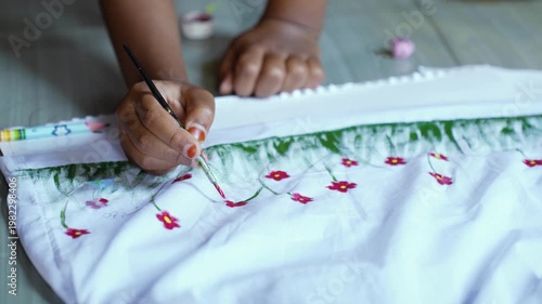 Young girl painting colorful floral patterns on white fabric for Pohela Boishakh festival, expressing child creativity, traditional Bengali culture, art education, and festive celebration. Drawing