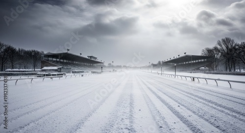 Snow covered race track under overcast sky showing bleachers and trees