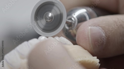 Expert technician performing delicate polishing on a dental bridge. Showcases craftsmanship in creating realistic dental implants and veneers.