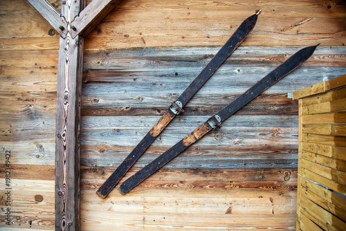Pair Of Traditional Vintage Skis Hanging On A Wooden Cabin Exterior