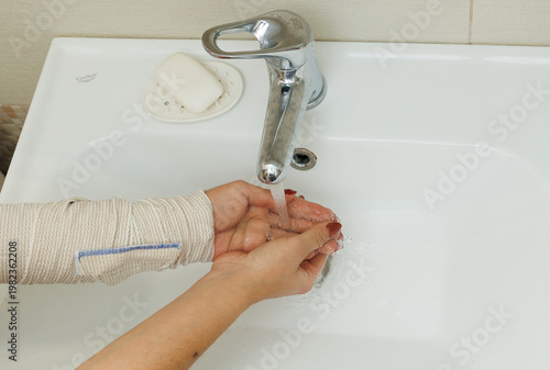 Woman washing hands in bathroom sink, hygiene routine