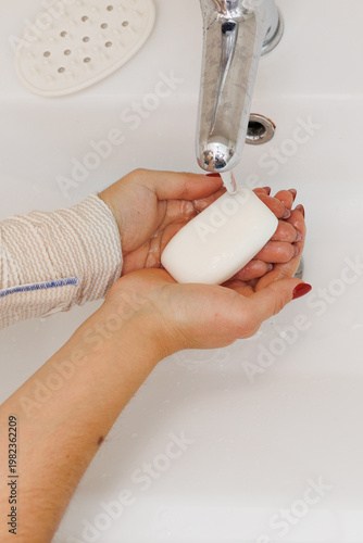 Woman washing hands in bathroom sink, hygiene routine