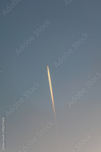 Airplane Flying High in Clear Blue Sky with Long White Contrail Vapor Trail Behind Aircraft Jet Engine Exhaust Path in Atmosphere Aviation and Travel Concept