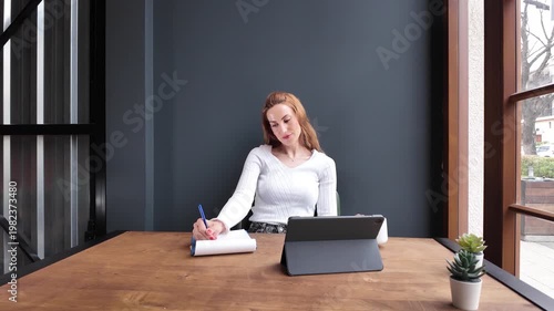 Relaxed woman taking coffee break while working on tablet at home office