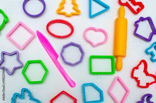 Colored plastic molds of different shapes for sculpting cookies or clay products on a light background.