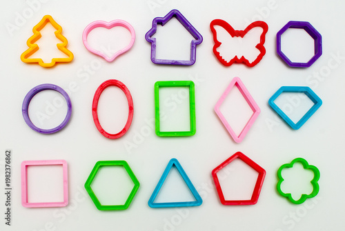 Colored plastic molds of different shapes for sculpting cookies or clay products on a light background.
