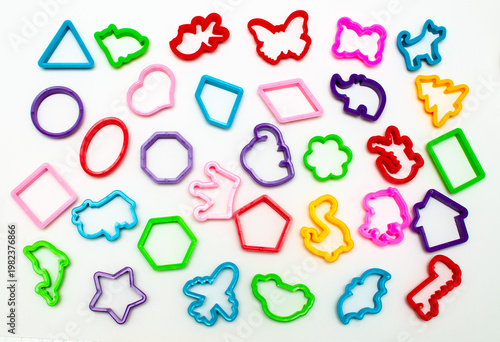 Colored plastic molds of different shapes for sculpting cookies or clay products on a light background.
