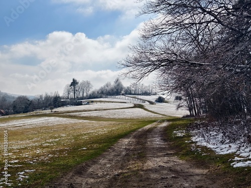 landscape with a dusty road and remnants of snow