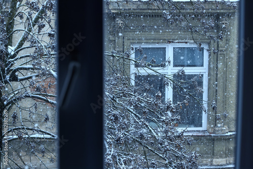 Tableau sur toile Snowy scene outside a window with a tree and building in the background on a col