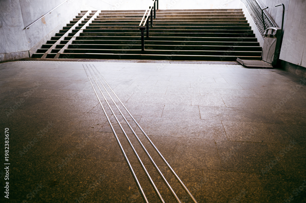 Fototapeta premium Tactile ground signs and guide strips assist navigation in a modern city infrastructure for all users at a busy stairway located in a public transport area