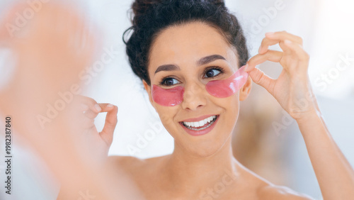 Tableau sur toile A woman smiles as she removes beauty patches from her face in front of a mirror