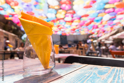 A yellow napkin inside a glass in one of the many bars overlooked by colorful umbrellas in Catania on a May day.