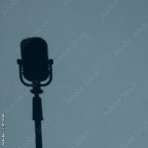 Silhouette of a classic dynamic microphone on stand against gray background