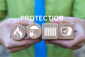 Concept of protection, security, defense. Business person holding wooden blocks with icons sees the text PROTECTION.