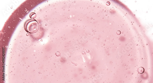 Soft pink gel background with pearl like sheen and delicate bubbles The texture is smooth and reflective, resembling a luxurious cosmetic serum