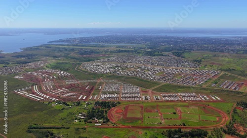 Drone pan from right to left over vast Itaembé Guazú neighborhood, revealing Posadas skyline and Paraná River bend toward Paraguay.