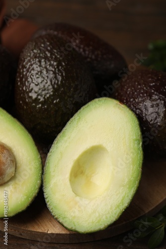 Whole and cut avocados on table, closeup