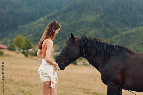 A young woman stands in a grassy field facing a calm horse, engaging in a gentle connection amid a wide countryside setting, conveying serenity, curiosity, and mindfulness outdoors.