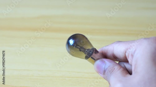 Hand holding light bulb on wood background