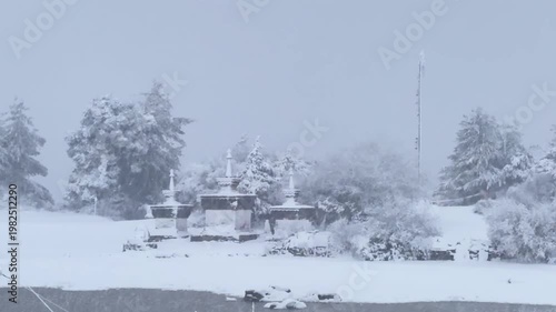 Peaceful cinematic footage of heavy snow falling over traditional Tibetan Buddhist stupas in a winter landscape.