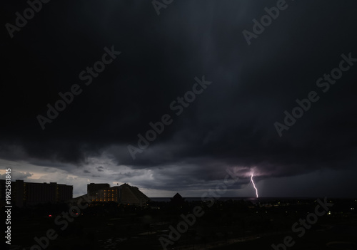 A striking photograph depicting a powerful lightning bolt illuminating the darkened sky over a nighttime landscape, illustrating nature’s force and raw energy in an atmospheric scene.