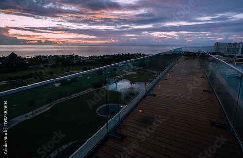 A stylish balcony provides an elevated view of a colorful dusk sky over a tropical landscape, perfect for relaxation and enjoying the beauty of nature.