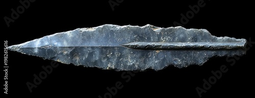 ancient flint spearhead with central ridge and flaked leaf-shaped blade on black background, sharp and austere