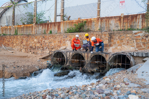 Engineers inspect water drainage system urban area safety assessment industrial site ground level environmental awareness