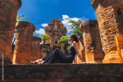 A female tourist sit on the background View of Po Nagar Cham towers complex