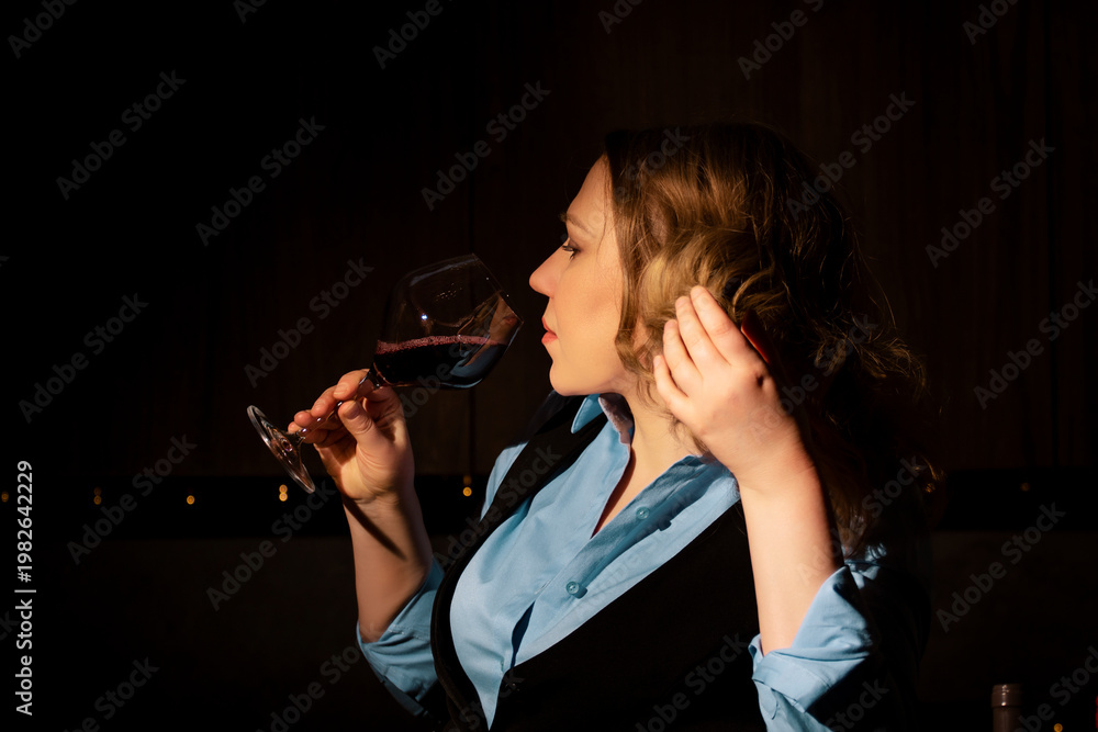 Naklejka premium Woman sommelier sniffing red wine aroma for professional flavor assessment. Olfactory analysis and expert evaluation of vineyard product.