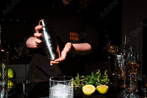 Bild auf Leinwand Woman bartender shaking cocktail in metal shaker with two hands