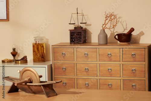 Traditional herbal medicine interior showing wooden drawers, grinding tool, and dried medicinal ingredients arranged on preparation table.