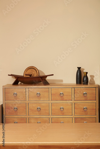 Minimal oriental medicine interior with wooden apothecary cabinet and empty wooden table for herbal preparation. Clean composition with copy space.